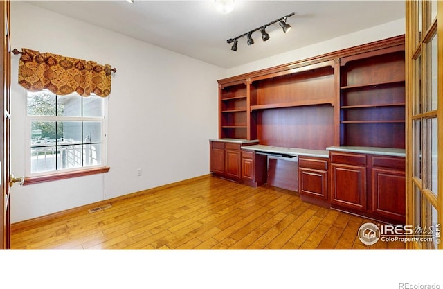 4447 Twin Peaks Dr, Loveland, CO 80537 - unfurnished office featuring built in desk, wood-type flooring, and rail lighting