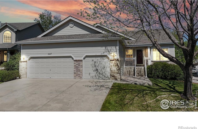4447 Twin Peaks Dr, Loveland, CO 80537 - view of front of property with a garage, concrete driveway, brick siding, and a yard