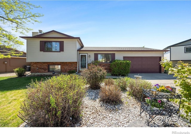 127 Lori Dr, Loveland, CO 80537 - tri-level home featuring an attached garage, concrete driveway, a chimney, and brick siding