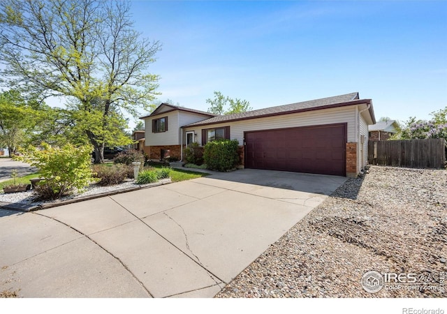 127 Lori Dr, Loveland, CO 80537 - split level home featuring brick siding, a garage, fence, and concrete driveway