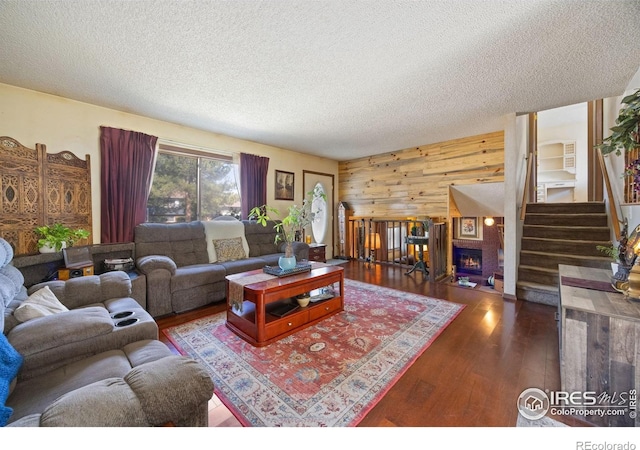 127 Lori Dr, Loveland, CO 80537 - living room featuring wood finished floors, a textured ceiling, wooden walls, stairs, and a lit fireplace