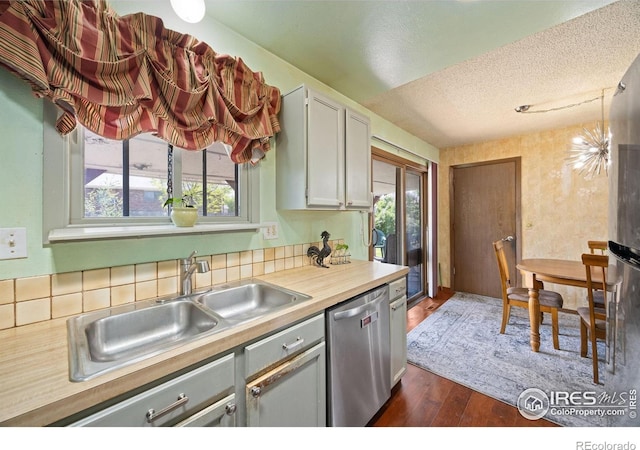 127 Lori Dr, Loveland, CO 80537 - kitchen with stainless steel appliances, a sink, a textured ceiling, light countertops, and dark wood-type flooring