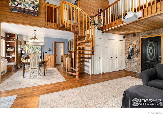 133 Rockledge Cir, Allenspark, CO 80540 - living area with stairway, a high ceiling, wooden walls, a chandelier, and wood finished floors