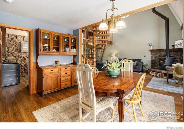 133 Rockledge Cir, Allenspark, CO 80540 - dining area with stairs, a wood stove, a chandelier, and dark wood finished floors