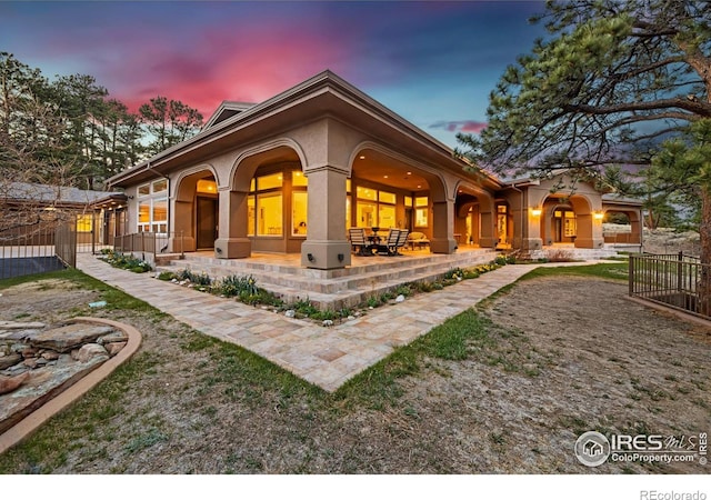 3005 Grey Fox Dr, Estes Park, CO 80517 - back of house at dusk featuring stucco siding, fence, and a patio