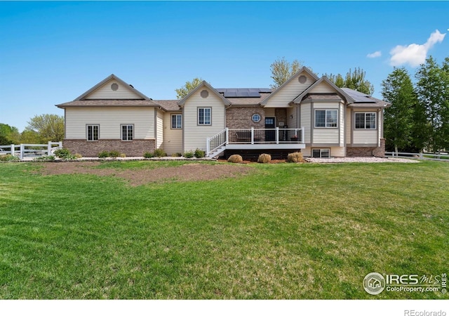 2015 Trail Ridge Dr, Severance, CO 80615 - view of front facade with solar panels, a wooden deck, brick siding, and roof with shingles
