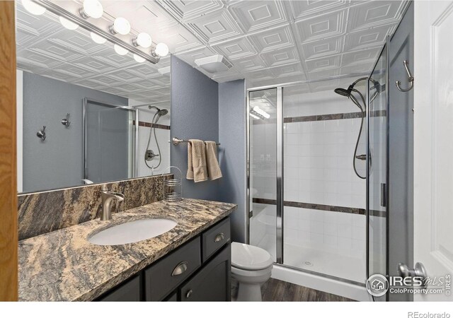 2015 Trail Ridge Dr, Severance, CO 80615 - full bath with an ornate ceiling, a shower stall, toilet, vanity, and wood finished floors