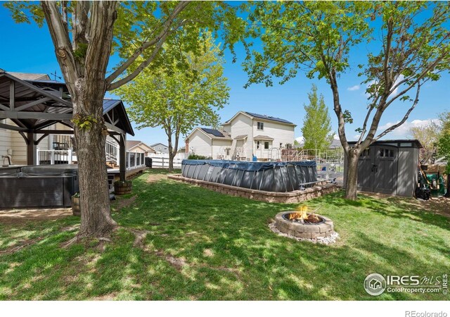 2015 Trail Ridge Dr, Severance, CO 80615 - view of green lawn with a storage shed, a fire pit, a gazebo, a hot tub, and a wooden deck