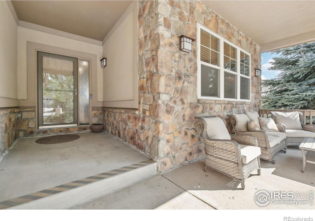 doorway to property with stone siding, a porch, and stucco siding