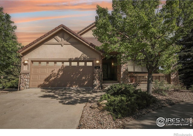 view of front of home with stone siding, driveway, an attached garage, and stucco siding