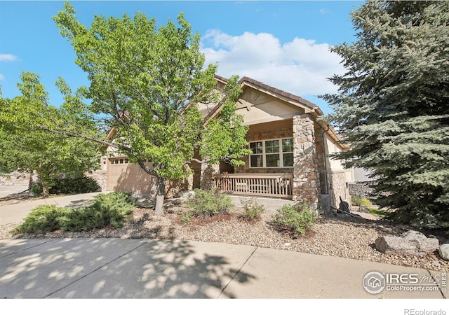 view of front of house with stone siding, covered porch, and concrete driveway