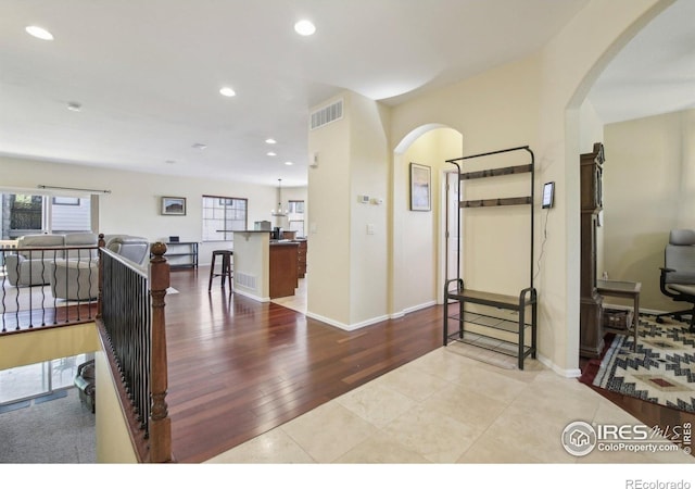 corridor featuring arched walkways, recessed lighting, wood finished floors, and baseboards