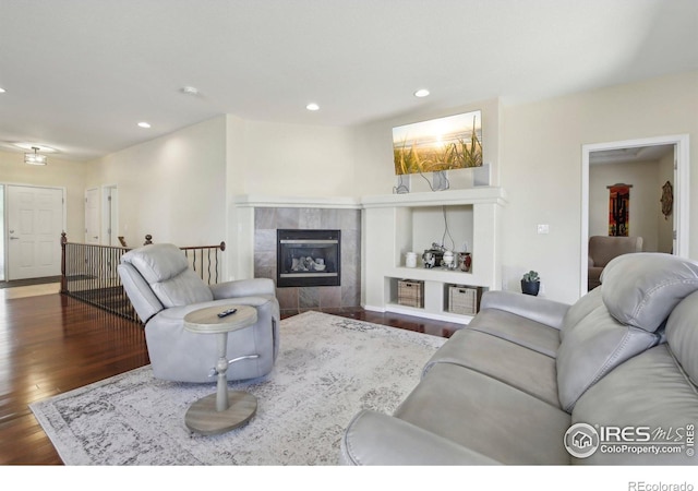 living room with wood finished floors, recessed lighting, and a tiled fireplace