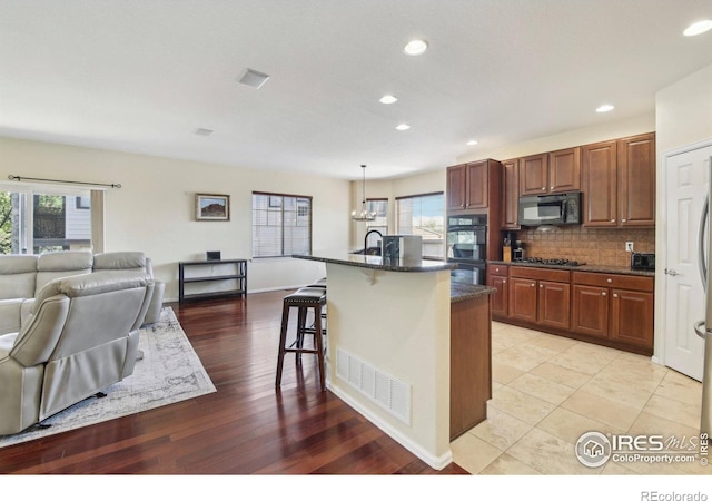 kitchen with black appliances, open floor plan, a breakfast bar area, decorative backsplash, and recessed lighting
