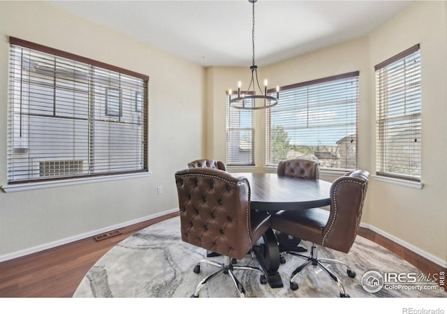 dining area featuring a chandelier, baseboards, wood finished floors, and a desk