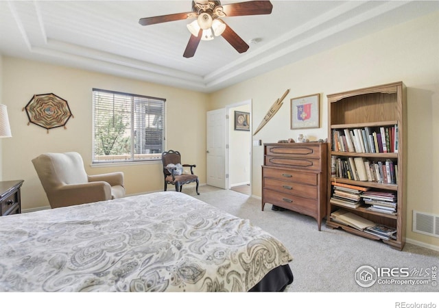 bedroom featuring carpet flooring, a tray ceiling, baseboards, and a ceiling fan