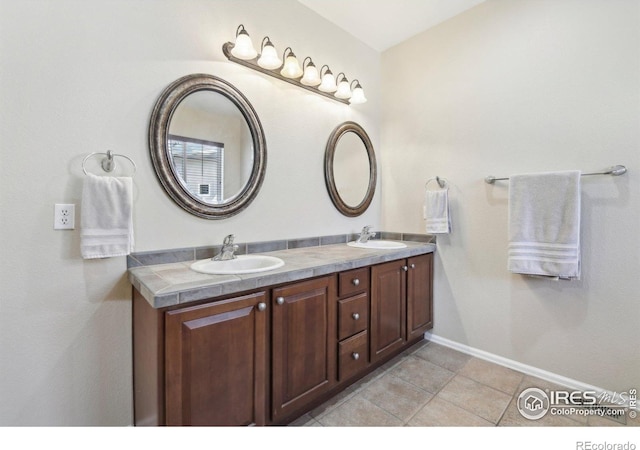 full bathroom with double vanity, baseboards, and tile patterned flooring