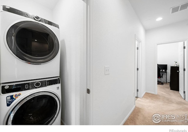clothes washing area with stacked washer / drying machine, light colored carpet, baseboards, and recessed lighting