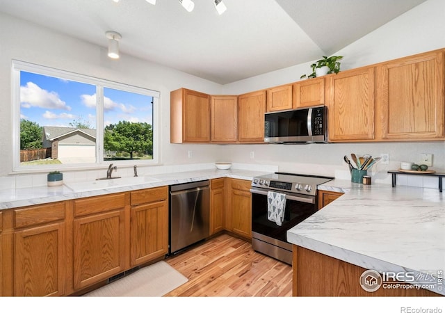 833 Kaitlyn Cir, Loveland, CO 80537 - kitchen featuring appliances with stainless steel finishes, light countertops, light wood finished floors, a sink, and brown cabinets