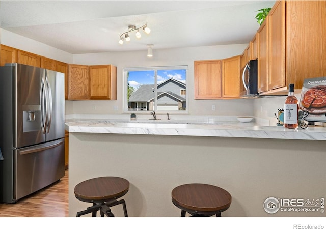 833 Kaitlyn Cir, Loveland, CO 80537 - kitchen featuring stainless steel appliances, a kitchen bar, a peninsula, and light wood-style floors