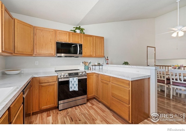 833 Kaitlyn Cir, Loveland, CO 80537 - kitchen featuring stainless steel appliances, a peninsula, lofted ceiling, light wood finished floors, and a ceiling fan