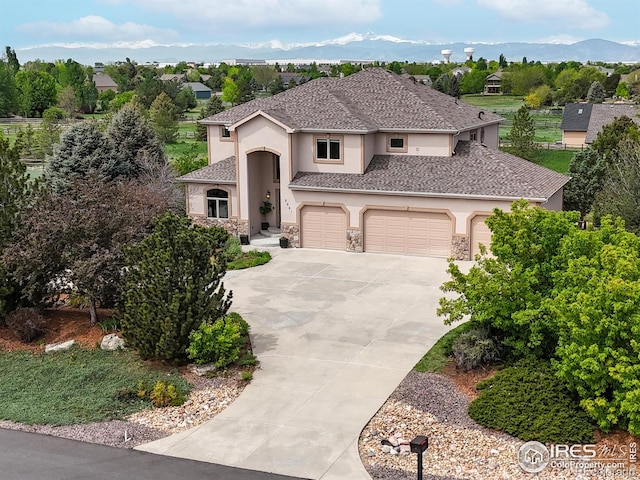 mediterranean / spanish-style house featuring stucco siding, a garage, concrete driveway, stone siding, and a mountain view