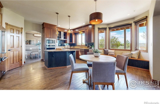 dining area with wood finished floors, recessed lighting, and arched walkways