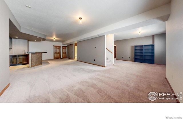 unfurnished living room featuring carpet floors, baseboards, wet bar, and recessed lighting