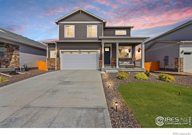 view of front of property with a porch, driveway, a garage, a front yard, and stone siding