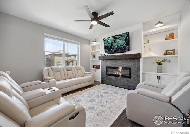 living area featuring dark wood-type flooring, a ceiling fan, a fireplace, and built in features