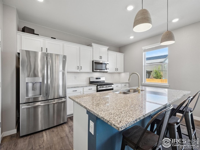 kitchen with stainless steel appliances, a sink, dark wood finished floors, a center island with sink, and white cabinetry