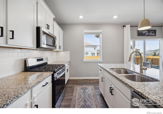 kitchen featuring stainless steel appliances, a sink, baseboards, dark wood-type flooring, and decorative backsplash