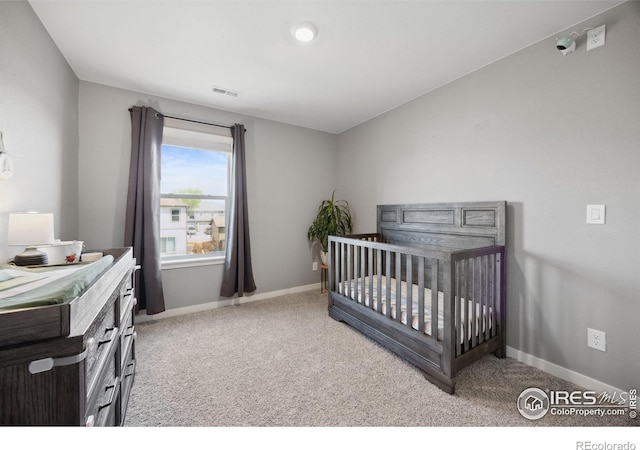 carpeted bedroom with baseboards and a crib