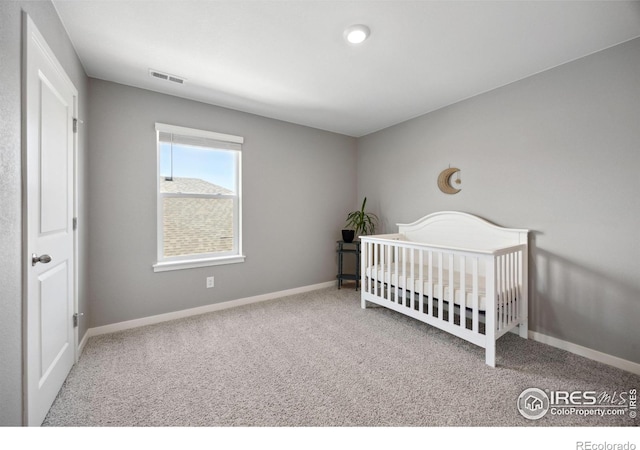 carpeted bedroom with baseboards and a crib