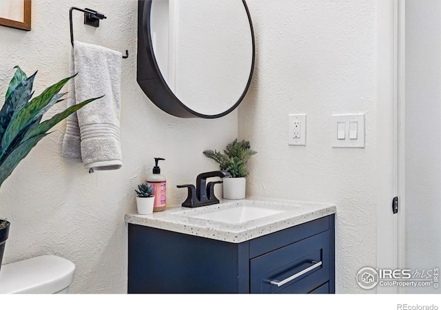 1805 W 22nd St, Loveland, CO 80538 - half bathroom with vanity, toilet, and a textured wall