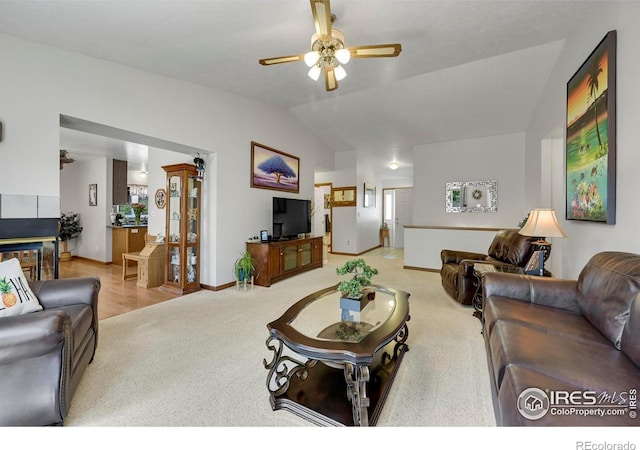 carpeted living room with ceiling fan, vaulted ceiling, and baseboards