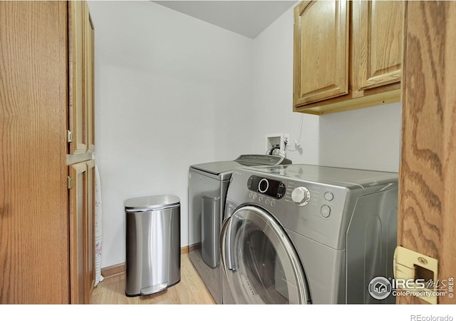 washroom featuring cabinet space, separate washer and dryer, light wood-type flooring, and baseboards