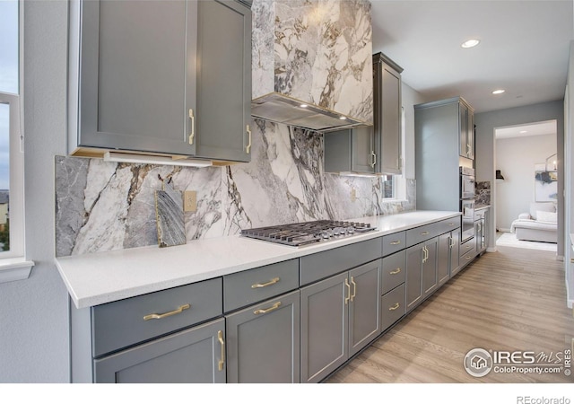 12917 Fox St, Broomfield, CO 80020 - kitchen featuring stainless steel gas cooktop, gray cabinetry, wall chimney range hood, light wood-type flooring, and recessed lighting