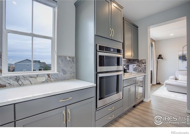 12917 Fox St, Broomfield, CO 80020 - kitchen with gray cabinets, backsplash, healthy amount of natural light, and stainless steel double oven