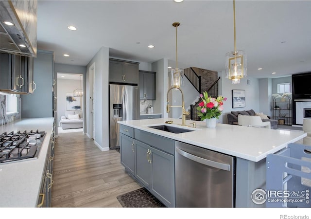 12917 Fox St, Broomfield, CO 80020 - kitchen with stainless steel appliances, a sink, under cabinet range hood, light wood-style floors, and open floor plan