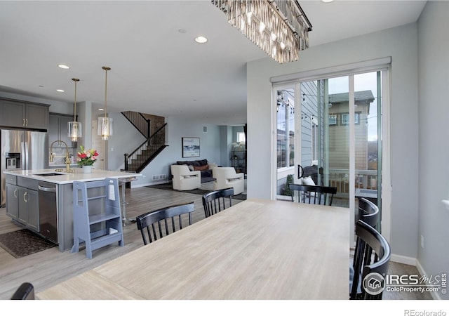 12917 Fox St, Broomfield, CO 80020 - dining area featuring stairway, light wood-type flooring, recessed lighting, baseboards, and a chandelier