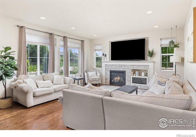 8265 Blackwood Dr, Windsor, CO 80550 - living area featuring wood finished floors, a stone fireplace, and recessed lighting