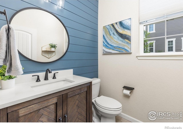 8265 Blackwood Dr, Windsor, CO 80550 - bathroom featuring toilet, vanity, wooden walls, and baseboards