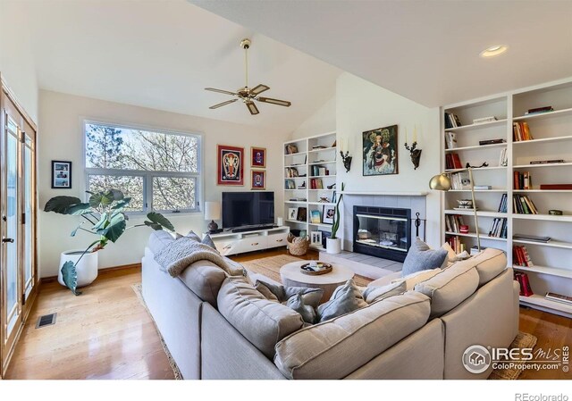 1149 Quince Ave, Boulder, CO 80304 - living area with light wood-style flooring, ceiling fan, a tiled fireplace, lofted ceiling, and built in shelves