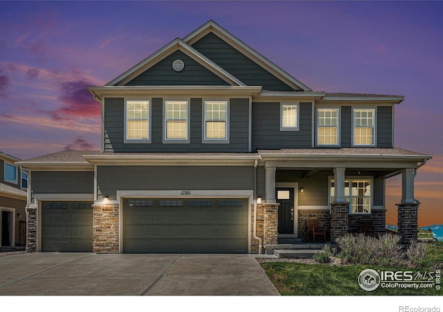 17101 Pecos St, Broomfield, CO 80023 - view of front of home featuring covered porch, stone siding, driveway, and an attached garage