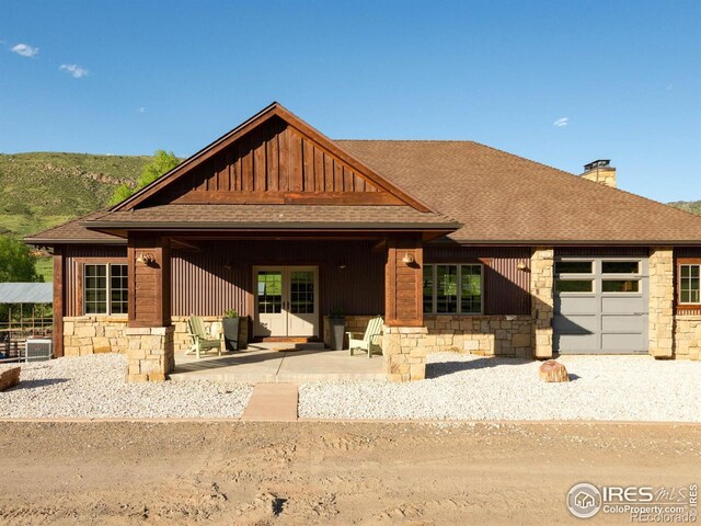 9840 Buckhorn Rd, Loveland, CO 80538 - view of front of home with stone siding, a shingled roof, a chimney, and board and batten siding