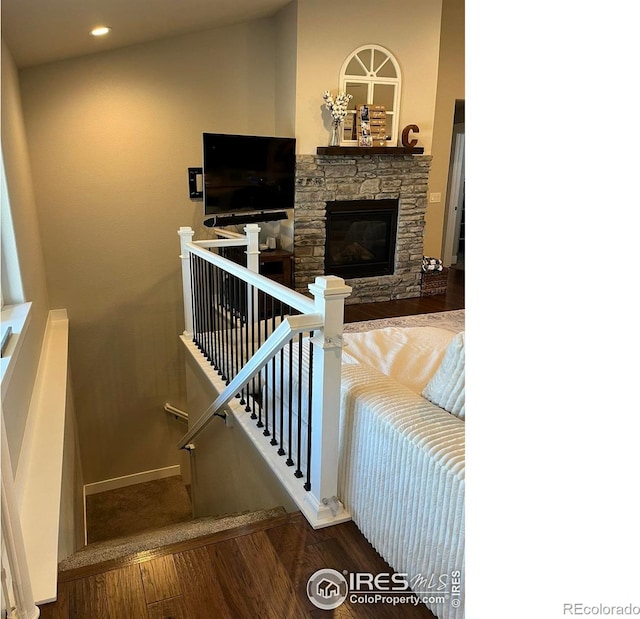 stairs with wood finished floors, a stone fireplace, baseboards, and recessed lighting