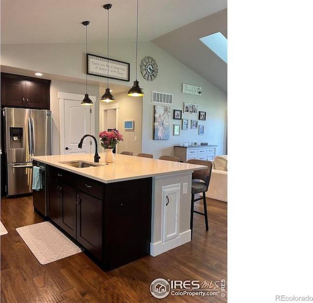 kitchen with stainless steel fridge, a sink, dishwasher, a breakfast bar area, and dark wood finished floors