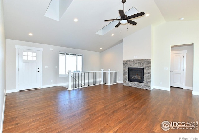 unfurnished living room featuring a skylight, ceiling fan, wood finished floors, high vaulted ceiling, and baseboards