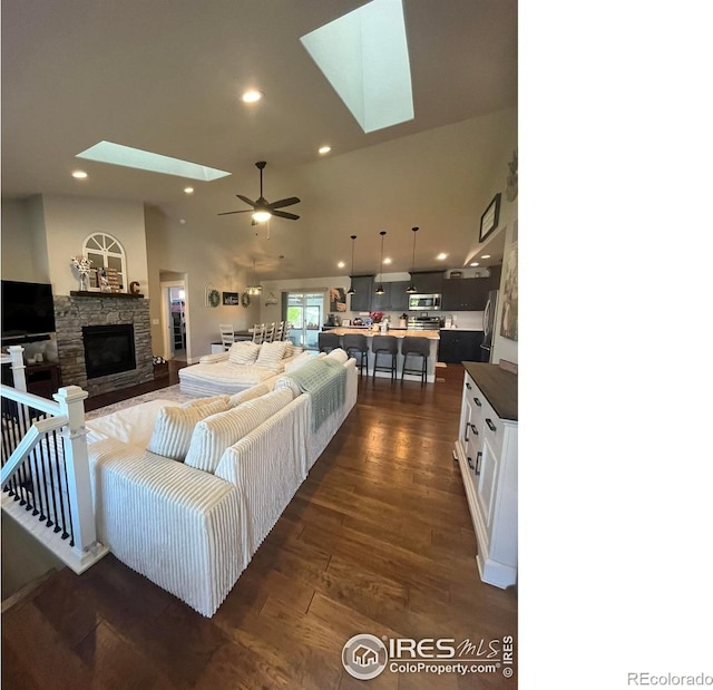 living room with a skylight, a fireplace, dark wood-style flooring, recessed lighting, and a ceiling fan